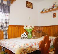 Innenraum einer Hütte mit Tisch, rustikaler Dekoration und Holzverkleidung an den Wänden.