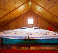 Eine Hütte mit Holzverkleidung hat ein Doppelbett unter einer Holzdecke.