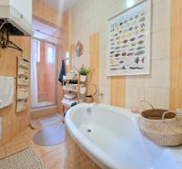 Badezimmer in einer 3-Zimmer-Wohnung mit Badewanne, Dusche und Körben für Zubehör.