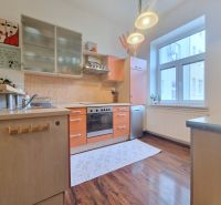 Küche mit orangefarbenen Schränken, Holzboden, in einer 3-Zimmer-Wohnung.