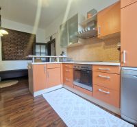 Küche in einer 3-Zimmer-Wohnung mit Holzboden und Ziegelwand.