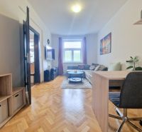 Wohnzimmer mit Holzboden, Sofa und Schreibtisch in einer 3-Zimmer-Wohnung.