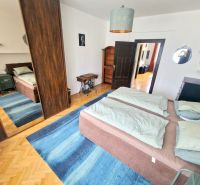 Schlafzimmer in einer 3-Zimmer-Wohnung mit Bett, Spiegelschrank und blauem Teppich.