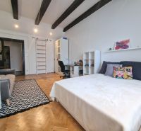 Ein Zimmer mit einem Bett, einem Sofa und einem Boden mit Holzdekor in einer 3-Zimmer-Wohnung.