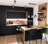 Stilvolle Küche mit schwarzen Schränken und Holzboden in einer 2-Zimmer-Wohnung.