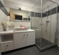 Badezimmer in einer 2-Zimmer-Wohnung mit verglaster Duschkabine und großem Spiegel.