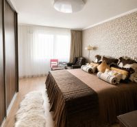 Schlafzimmer in einer 2-Zimmer-Wohnung mit Holzboden, gemütlichem Bett und gemusterten Tapeten.