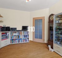 Ein Zimmer in einer 4-Zimmer-Wohnung mit Regalen, Schränken, Büchern und einem Boden in Holzoptik.