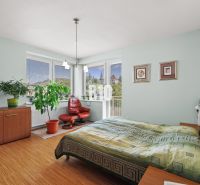 Schlafzimmer in einer 4-Zimmer-Wohnung mit Holzboden, Sessel und Pflanzen.