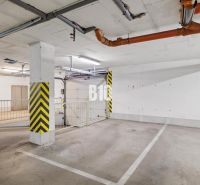 Unterirdischer Parkplatz in einer 4-Zimmer-Wohnung mit gelben Sicherheitsstreifen und Rohrleitungen.