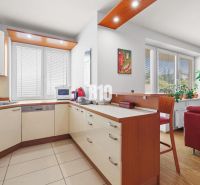 Küche in einer 4-Zimmer-Wohnung mit Eckküche, Bartresen und hellem Interieur.