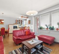 Wohnzimmer in einer 4-Zimmer-Wohnung mit roten Sofas und einem Boden in Holzoptik.
