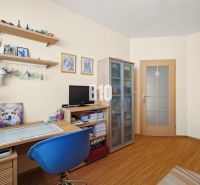 Ein Arbeitszimmer in einer 4-Zimmer-Wohnung mit Regalen, Holzmöbeln und einem Boden in Holzoptik.