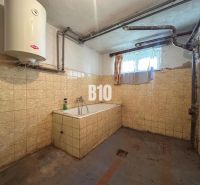 Badezimmer in einem Einfamilienhaus mit Fliesen und Badewanne, mit niedrigem Fenster und Gasheizung.