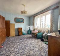 Ein Zimmer in einem Einfamilienhaus mit Teppich, Schränken und einem Sessel unter dem Fenster.