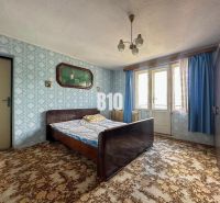 Schlafzimmer in einem Einfamilienhaus mit gemustertem Teppich und blauen Vorhängen.