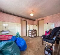 Innenraum eines Einfamilienhauses mit Waschbecken, Holzboden und gelagerten Gegenständen.