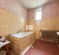 Ein Badezimmer in einem Einfamilienhaus mit einer Badewanne und keramischen Fliesen an den Wänden.