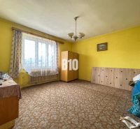 Ein Zimmer in einem Einfamilienhaus mit Teppich, Möbeln und Vorhängen am Fenster.