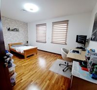 Ein Zimmer in einem Einfamilienhaus mit einem Bett, einem Schreibtisch und einem Boden mit Holzdekor.