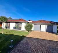 Ein Einfamilienhaus in Nové Zámky mit rotem Dach, Garage und gepflegtem Rasen.