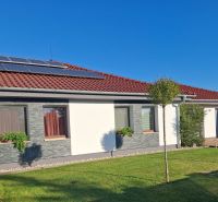 Ein Einfamilienhaus in Nové Zámky mit Solarpaneelen auf dem Dach und einem gepflegten Garten.
