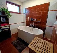 Badezimmer in einem Einfamilienhaus mit Badewanne, Regal und Wäschekorb.