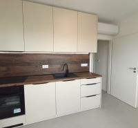 Küche in einer 2-Zimmer-Wohnung mit weißen Schränken und Holzboden.