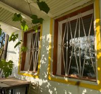 Ein Fenster mit gelbem Rahmen und Gitter, überflutet von Sonnenlicht in einer Hütte in Banka.