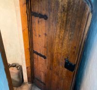 Alte Holztüren in der Hütte mit sichtbarem Kanister im engen Raum.