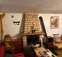 Ein Zimmer in einer Hütte mit Kamin, Holzstühlen und mehreren Weinflaschen auf dem Tisch.