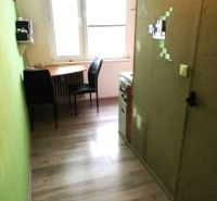 Küche in einer Einzimmerwohnung mit Holzboden-Dekor und einem Tisch am Fenster.