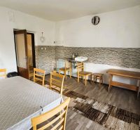 Esszimmer in einem Einfamilienhaus mit Holzboden, einfachem Möbel und Waschbecken.