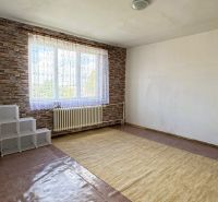 Ein Zimmer mit einem großen Fenster, einem Teppich und einer Ziegelmusterwand in einem Einfamilienhaus.