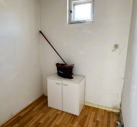 Ein kleiner Raum mit einem Fenster, einem Schrank und einem Boden mit Holzdekor in einem Einfamilienhaus.