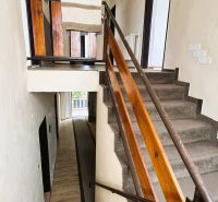 Eine Treppe im Einfamilienhaus mit einem Holzgeländer und einem Teppich auf den Stufen.