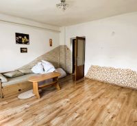 Wohnzimmer in einem Einfamilienhaus mit Sofa und Boden in Holzoptik.