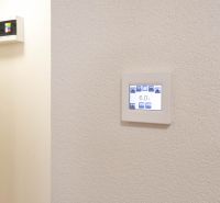 Ein einstellbares Thermostat an der Wand in einem Studio-Apartment, schlichtes Design, weißer Hintergrund.
