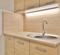 Küchenzeile in einem Einzimmerapartment mit Holzdekor und Spülbecken.