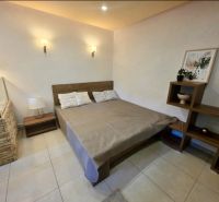 Schlafzimmer in einer Einzimmerwohnung mit stilvollem Dekor, Holzelementen, geräumigem Bett.