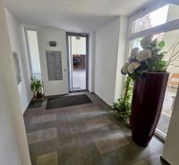 Eingangshalle mit Blumen und Briefkästen, heller Raum.