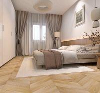 Schlafzimmer mit Vorhängen, Bett und Holzboden in einer 2-Zimmer-Wohnung.