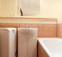 Badezimmer in einer 2-Zimmer-Wohnung mit Badewanne und Waschmaschine, gefliest mit bunten Fliesen.