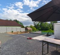 Ein Hof mit steinernem Belag und einem großen Sonnenschirm auf den Erholungsgrundstücken in Záhorce, Selešťany.
