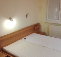 Schlafzimmer einer 3-Zimmer-Wohnung mit einem Holzbett und einem Fenster mit Rollläden an der Wand.