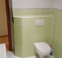 Badezimmer mit weißen und grünen Fliesen in einer 3-Zimmer-Wohnung, WC und Waschbecken.