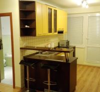 Küchenecke mit gelben Schränken und Theke in einer 3-Zimmer-Wohnung, Boden mit Holzdekor.