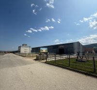 Industriegebäude in Hniezdne mit klarem blauen Himmel und Zufahrtsstraße.