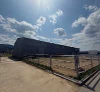 Ein Gebäude in Hniezdne, ein eingezäunter Bereich mit Pferden, sonniger Himmel, leicht bewölkt.