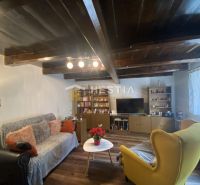 Wohnzimmer in einem Einfamilienhaus mit Holzdecke, bequemen Sitzgelegenheiten und dekorativer Beleuchtung.